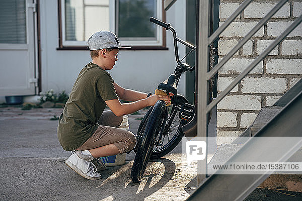 Junge reinigt bmx Fahrrad auf dem Hof
