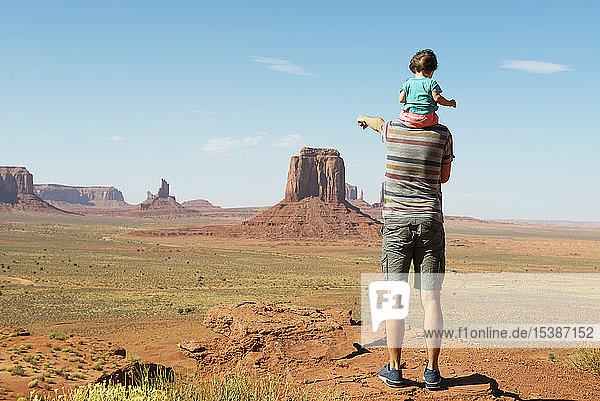 USA  Utah  Monument Valley  Father traveling with baby  girl on shoulders and pointing to Monument Valley landscape
