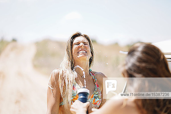 Zwei glückliche junge Frauen im Bikini  die Wasser spritzen