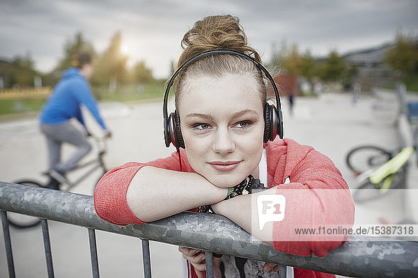 Portrait of teenage girl wearing headphones at a skatepark