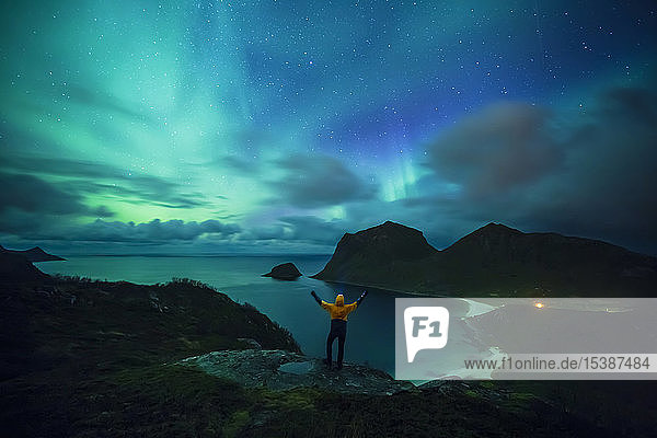 Norway Lofoten Islands Haukland Beach northern lights man with raised arms