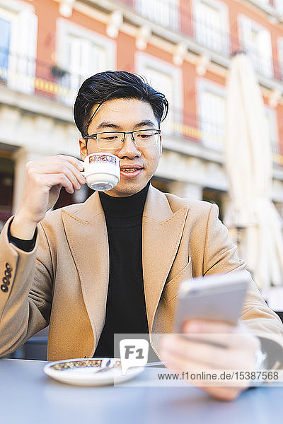 Spanien  Madrid  junger Mann benutzt Handy in einem Café am Plaza Mayor