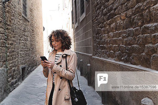 Woman standing in an alley using cell phone
