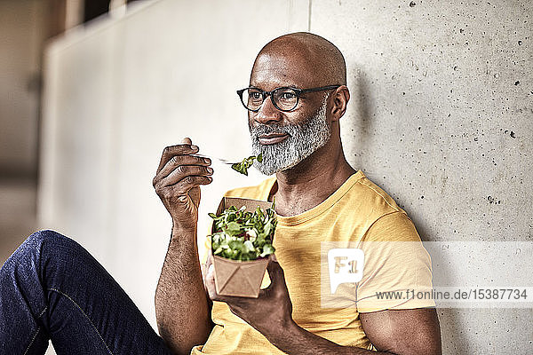 Ein reifer Geschäftsmann macht Mittagspause und isst einen Salat