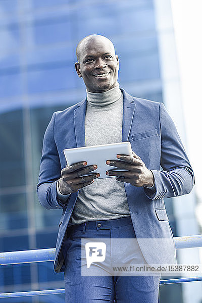Porträt eines lächelnden Geschäftsmannes mit digitalem Tablet im Freien