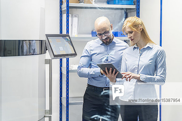 Geschäftsmann und Geschäftsfrau betrachten Tablet am 3D-Drucker