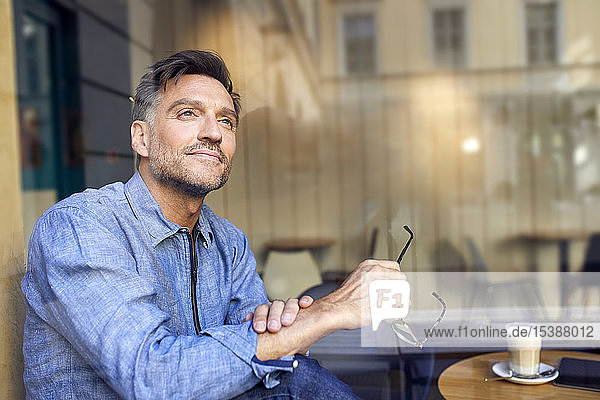 Porträt eines Mannes hinter einer Fensterscheibe in einem Cafe