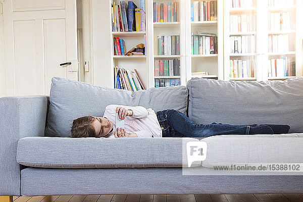 Girl lying on couch at home holding cell phone