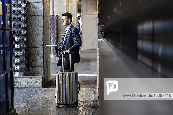Businessman with suitcase standing on station platform