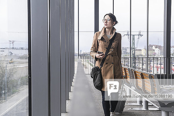 Geschäftsfrau zu Fuß mit Gepäck und Mobiltelefon