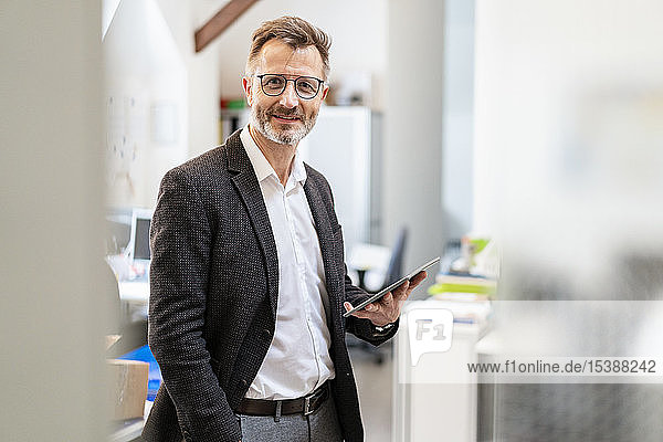 Porträt eines lächelnden Geschäftsmannes mit Tablett im Büro