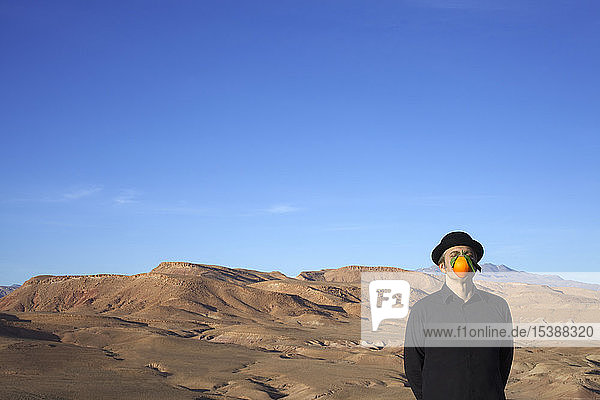 Morocco  Ounila Valley  man wearing a bowler hat with an orange in front of his face