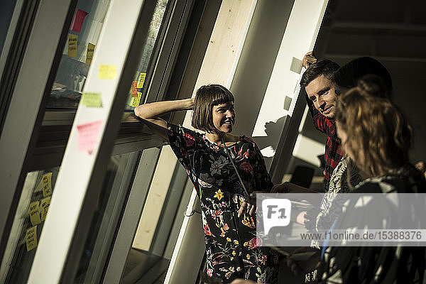 Colleagues brainstorming in office standing at the window