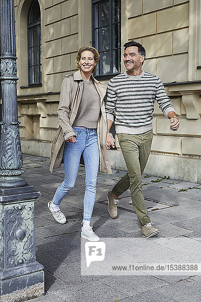 Glückliches Paar beim Spaziergang auf dem Bürgersteig in der Stadt