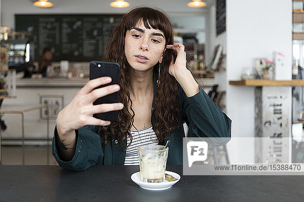 Young woman using cell phone in a cafe
