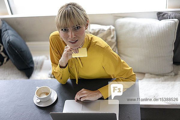 Blonde Frau macht Online-Zahlungen mit ihrer Kreditkarte