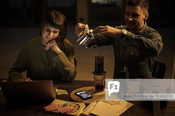 Colleagues sitting in office working late drinking coffee