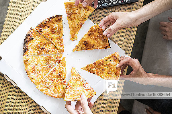 Freunde essen Pizza aus einer Schachtel  nehmen Stücke