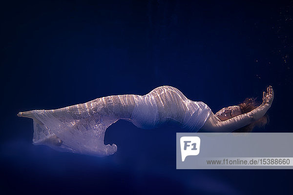 Pregnant woman wearing white dress under water
