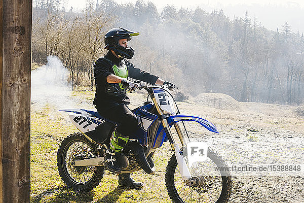 Motocross-Fahrer auf Motorrad mit aus dem Auspuffrohr austretendem Rauch