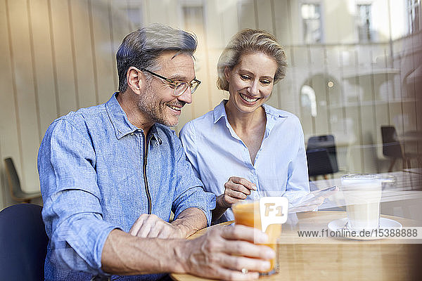 Happy woman and man using tablet in a cafe