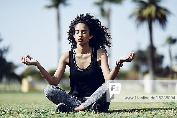 Sporty young woman doing yoga on lawn