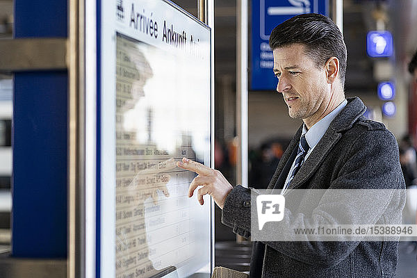 Businessman checking departures board at the train station