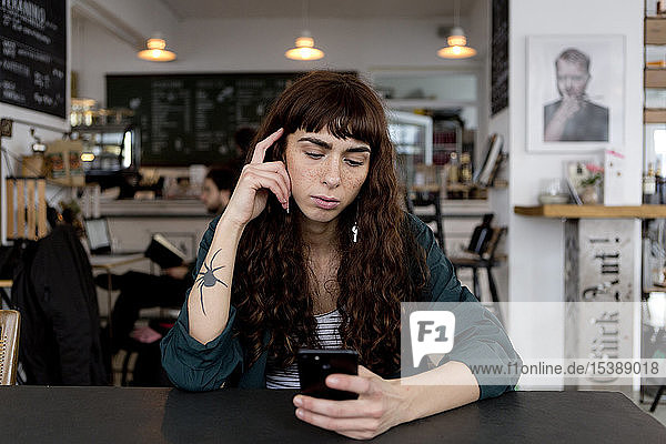 Junge Frau benutzt Handy in einem Café