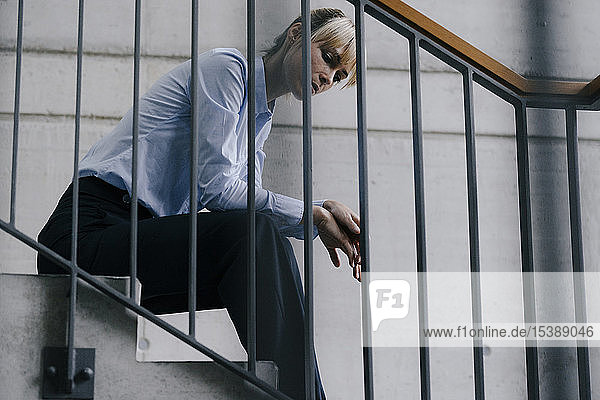 Erschöpfte Geschäftsfrau sitzt auf der Treppe