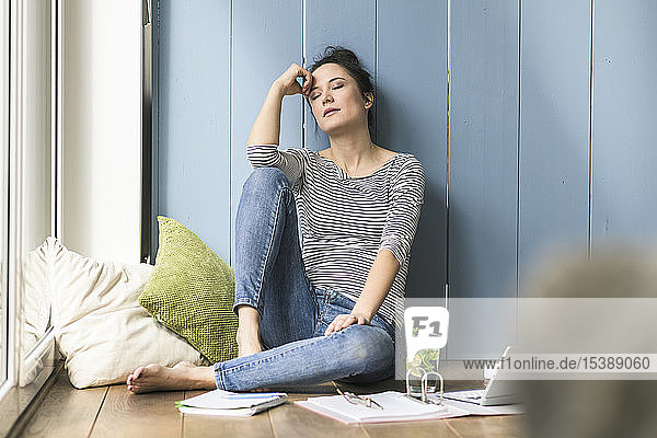 Relaxed woman sitting at the window at home having a break