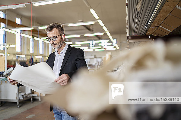 Businessman with plan in factory warehouse