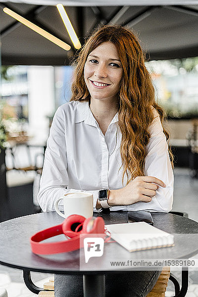 Junge Geschäftsfrau sitzt im Café und lächelt