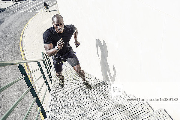 Mann in schwarzer Sportkleidung rennt die Treppe hinauf