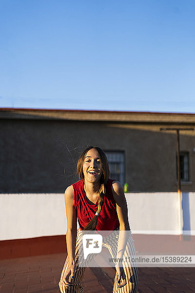 Porträt eines glücklichen Teenager-Mädchens auf der Dachterrasse bei Sonnenuntergang