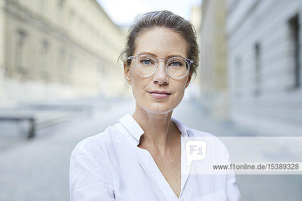 Porträt einer selbstbewussten Frau mit Brille und weißem Hemd in der Stadt