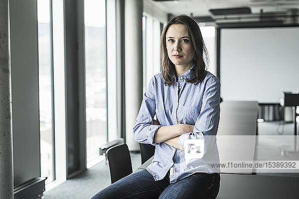 Portrait of serious businesswoman sitting on conference table in office