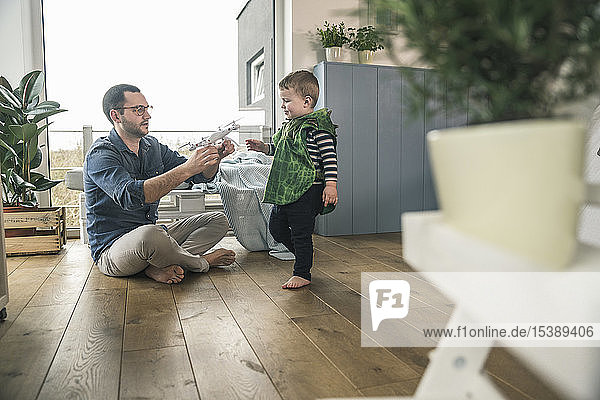Boy in a costume and father playing with a drone at home