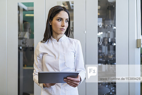 Woman with tablet wearing lab coat in modern factory