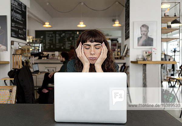 Frustrierte junge Frau mit Laptop in einem Café