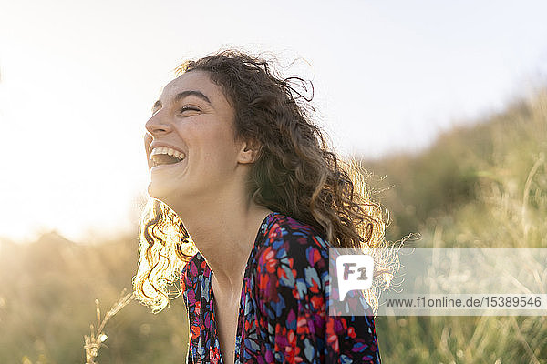 Porträt einer jungen Frau auf einer Wiese stehend  lachend