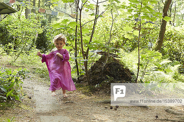 Kleines Mädchen mit rosa Tunika läuft in der Natur