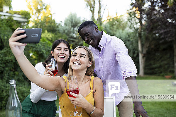 Friends having fun at a summer dinner in the garden  taking selfies