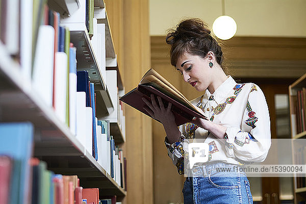 Female student reading book in a public library