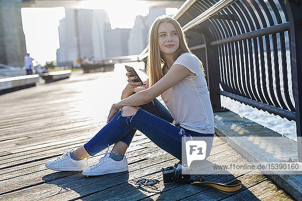 Junge Frau erkundet New York City  macht eine Pause  benutzt ein Smartphone