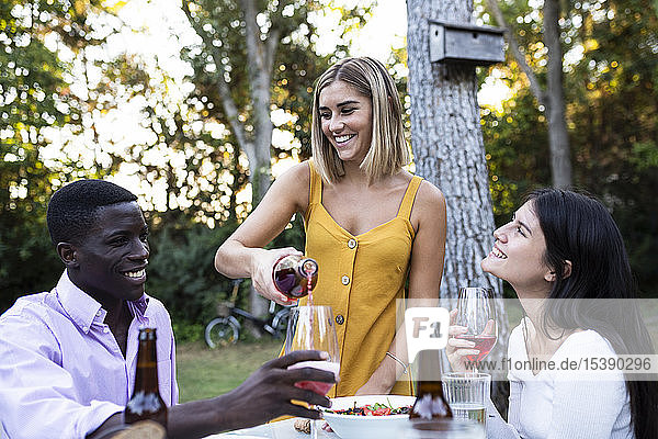 Gastgeber gießt Wein in Gläser bei einem sommerlichen Abendessen im Garten