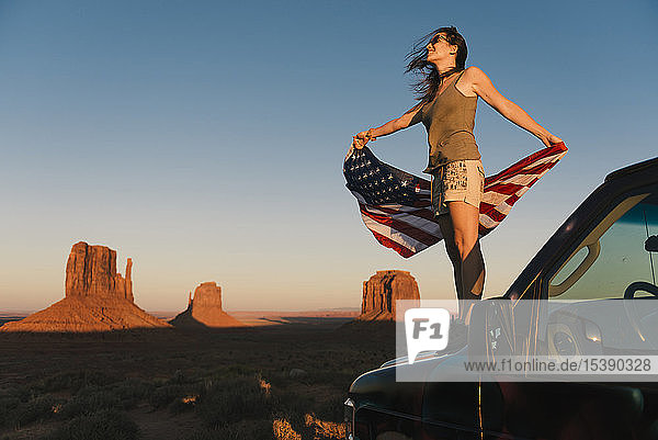 USA  Utah  Monument Valley  Woman with United States of America flag enjoying the sunset in Monument Valley