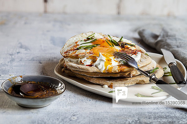 Fladenbrot mit Knoblauchjoghurt, Spiegelei und Chilibutter auf Schneidebrett