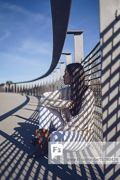 Young woman sitting on a bridge