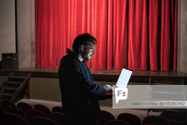 Regisseur steht mit Laptop im Theatersaal