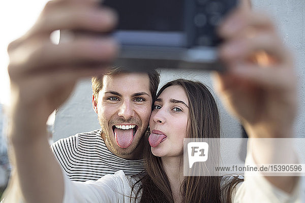 Verspieltes junges Paar  das ein Selfie mit herausgestreckter Zunge